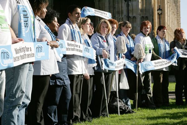 British National Health Service (NHS) staff gather outside Houses of Parliament in London to voice their feelings against potential staff cuts in hospitals, Wednesday, Nov. 1, 2006.. British National Health Service (NHS) staff gather outside Houses of Parliament in London to voice their feelings against potential staff cuts in hospitals, Wednesday, Nov. 1, 2006.. - Sputnik International
