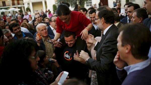 Prime Minister Mariano Rajoy (R) helps a woman to get down from the shoulders of a man before an electoral rally to open the electoral pre-campaign of the People's Party (PP) for the Spanish general elections, in Cabra, southern Spain, October 29, 2015 - Sputnik International
