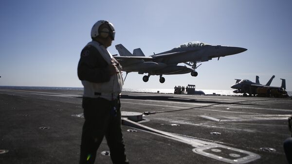 A US Navy crew member looks at an F/A-18 Super Hornet fighter landing onto the deck of the USS Ronald Reagan, a Nimitz-class nuclear-powered aircraft carrier, during a joint naval drill between South Korea and the US in the West Sea off South Korea on October 28, 2015 - Sputnik International