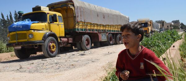 A Syrian child eats as he sits near a convoy of trucks from the World Food Programme and UNICEF carrying international aid as they drive in the countryside of the Homs district en route to the rebel held area of Al-Rastan north of the central Syrian city of Homs, on April 21, 2015. A Syrian child eats as he sits near a convoy of trucks from the World Food Programme and UNICEF carrying international aid as they drive in the countryside of the Homs district en route to the rebel held area of Al-Rastan north of the central Syrian city of Homs, on April 21, 2015. - Sputnik International