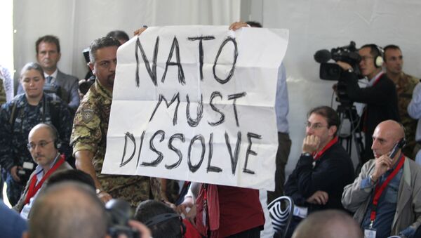 A protestor shows a poster reading Nato Must Dissolve during a press conference following the opening ceremony of NATO’s large scale exercise Trident Juncture 2015 at the Italian Air Force Base in Trapani, Sicily - Sputnik International