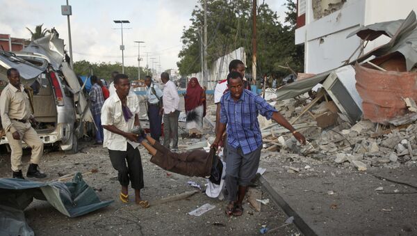 Somali men carry a wounded person to an ambulance outside the Sahafi Hotel in Mogadishu, Somalia Sunday, Nov. 1, 2015 - Sputnik International