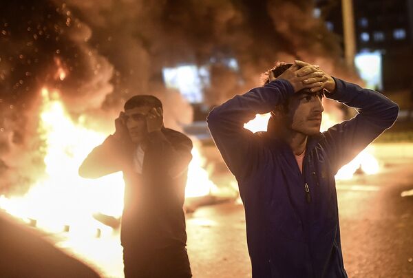 People react as smoke billows from burning pallets set on fire during clashes between Turkish riot policemen and Kurdish protesters in the southeastern city of Diyarbakir on November 1, 2015 after first results of the Turkish general election showed a clear victory to the Justice and Development Party (AKP). Turkish police fired tear gas and water cannon at Kurds who were protesting after the election appeared to deliver a clear victory to AKP, an AFP photographer said. Latest results say the pro-Kurdish People's Democratic Party (HDP) won slightly over 10 percent of the vote, just enough to scrape into parliament.  - Sputnik International