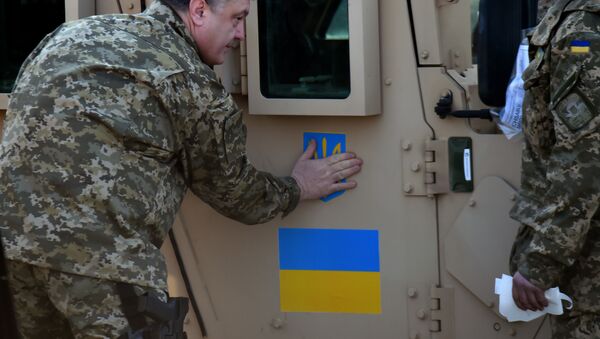 Ukrainian President Petro Poroshenko sticks an Ukrainian flag and the state emblem on an armoured vehicle at Kiev airport on March 25, 2015 during a welcoming ceremony of the first US plane delivery of non-lethal aid, including 10 Humvee vehicles - Sputnik International