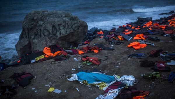 The body of a young man covered with a blue blanket remains on Eftalou beach after his dinghy capsized on the northeastern Greek island of Lesbos, Friday, Oct. 30, 2015. - Sputnik International