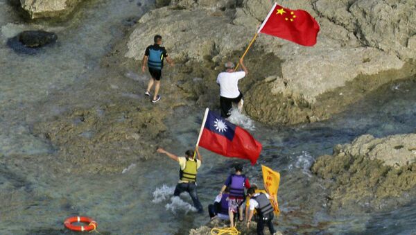 Activists in Taiwan carrying Chinese and Taiwanese national flags on the disputed island known as Senkaku in Japan and Diaoyu in China after arriving on their boat, west of Japan's sourthern island of Okinawa, August 12, 2012. - Sputnik International