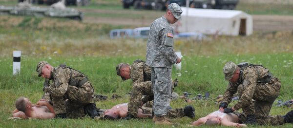 US serviceman teaches Ukrainian soldiers how to give emergency medical aid during the Rapid Trident/Saber Guardian 2015 military exercises at the International Peacekeeping and Security Centre base outside Lviv, Ukraine, Friday, July 24, 2015 US serviceman teaches Ukrainian soldiers how to give emergency medical aid during the Rapid Trident/Saber Guardian 2015 military exercises at the International Peacekeeping and Security Centre base outside Lviv, Ukraine, Friday, July 24, 2015 - Sputnik International