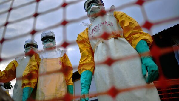 A file picture taken on August 14, 2014 shows Medecins Sans Frontieres (MSF) medical staff wearing protective clothing treating the body of an Ebola victim at their facility in Kailahun. - Sputnik International