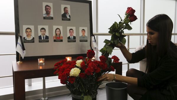 A woman places flowers in front of the portraits of crew members of the crashed Airbus A321 plane, operated by Russian airline Kogalymavia, in the company's office in Moscow, Russia November 2, 2015 - Sputnik International