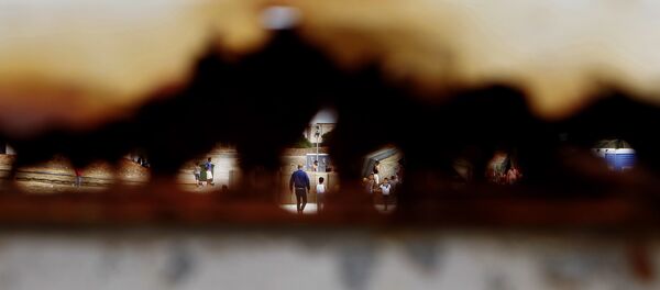 Migrants walk are seen through a hole of the rusty main gate at the temporary transit facility in Dhekelia Garrison, a British military base on the east Mediterranean island of Cyprus on Wednesday, Oct. 28, 2015. - Sputnik International