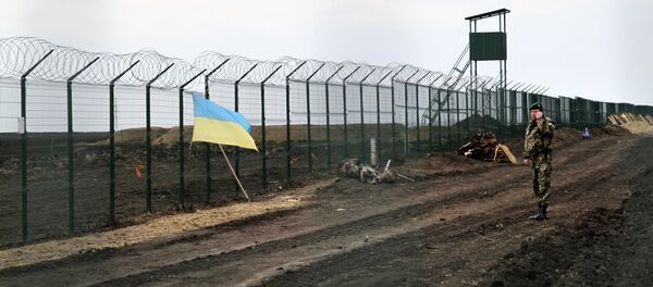 Ukrainian border guard officer speaks on a phone near a national flag attached to the fence on the Ukrainian-Russian border near Hoptivka, Kharkiv region, eastern Ukraine Ukrainian border guard officer speaks on a phone near a national flag attached to the fence on the Ukrainian-Russian border near Hoptivka, Kharkiv region, eastern Ukraine - Sputnik International