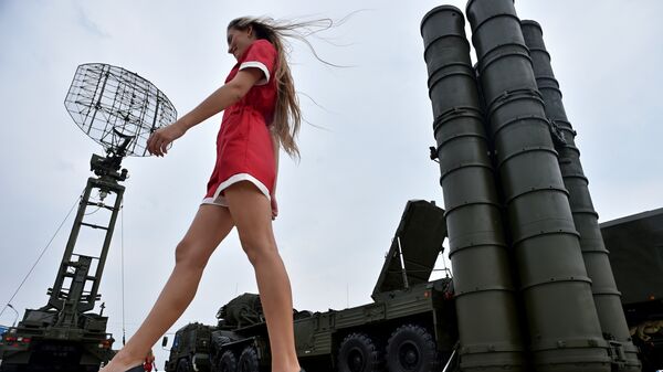 A woman walks near Russia's air defence system S-400 Triumf launch vehicles at the military exhibition - Sputnik International