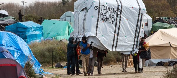 Migrant men move a tent in the New Jungle migrant camp in Calais on November 12, 2015. Migrant men move a tent in the New Jungle migrant camp in Calais on November 12, 2015. - Sputnik International