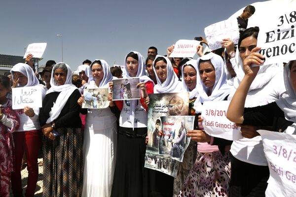 Yazidi Kurdish women hold posters during a protest against the Islamic State group's invasion on Sinjar city one year ago, in Dohuk, northern Iraq. Yazidi Kurdish women hold posters during a protest against the Islamic State group's invasion on Sinjar city one year ago, in Dohuk, northern Iraq. - Sputnik International