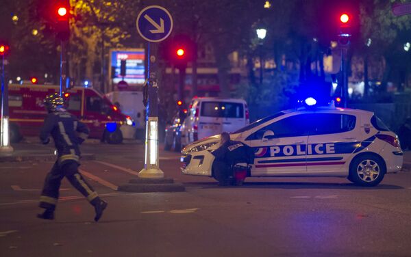 A police officer takes cover behind a car while a rescue worker runs outside the Bataclan theater in Paris, France, Wednesday, Nov. 13, 2015. A police officer takes cover behind a car while a rescue worker runs outside the Bataclan theater in Paris, France, Wednesday, Nov. 13, 2015. - Sputnik International