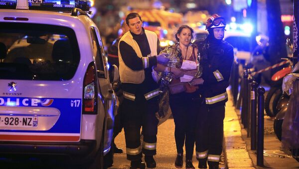 Rescue workers help a woman after a shooting, outside the Bataclan theater in Paris, Friday Nov. 13, 2015. - Sputnik International