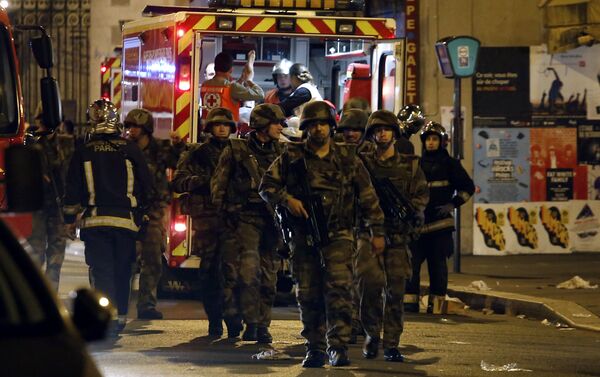 Soldiers walk in front of an ambulance as rescue workers evacuate victims near La Belle Equipe, rue de Charonne, at the site of an attack on Paris on November 14, 2015 - Sputnik International