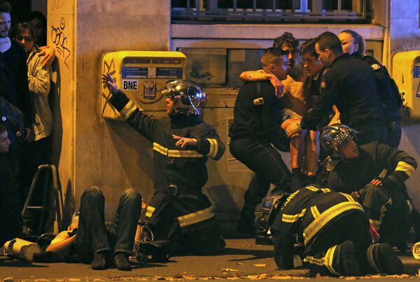 French fire brigade members aid an injured individual near the Bataclan concert hall following fatal shootings in Paris, France, November 13, 2015 - Sputnik International
