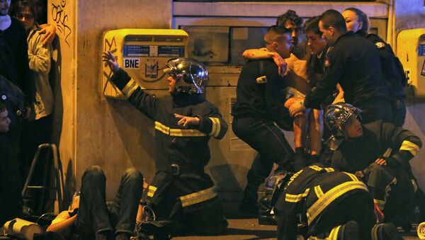 French fire brigade members aid an injured individual near the Bataclan concert hall following fatal shootings in Paris, France, November 13, 2015 - Sputnik International