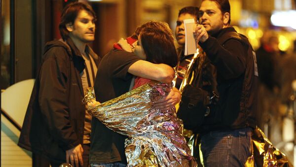 People hug each other before being evacuated by bus, near the Bataclan concert hall in central Paris, on November 14, 2015 - Sputnik International