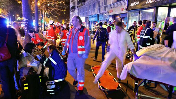 People rest on a bench after being evacuated from the Bataclan theater after a shooting in Paris, Saturday, Nov. 14, 2015 - Sputnik International