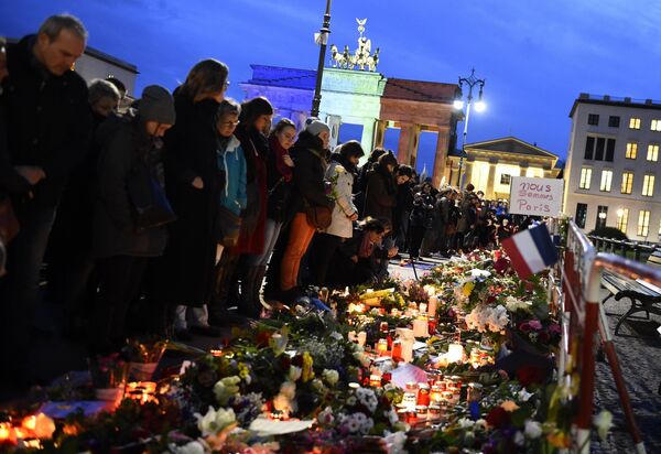 A banner reading 'We are Paris ' is pictured among candles and flowers in front of the Brandenbourg Gate outside the French embassy in Berlin, on November 14, 2015 a day after deadly attacks in Paris A banner reading 'We are Paris ' is pictured among candles and flowers in front of the Brandenbourg Gate outside the French embassy in Berlin, on November 14, 2015 a day after deadly attacks in Paris - Sputnik International