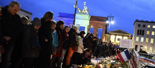 A banner reading 'We are Paris ' is pictured among candles and flowers in front of the Brandenbourg Gate outside the French embassy in Berlin, on November 14, 2015 a day after deadly attacks in Paris A banner reading 'We are Paris ' is pictured among candles and flowers in front of the Brandenbourg Gate outside the French embassy in Berlin, on November 14, 2015 a day after deadly attacks in Paris - Sputnik International