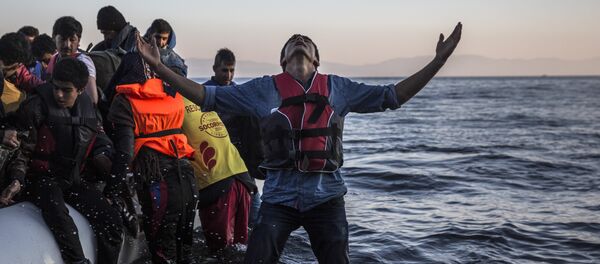 A young man gestures after disembarking from a dinghy at a beach on the Greek island of Lesbos after crossing the Aegean sea from the Turkish coast, Saturday, Nov. 14, 2015 - Sputnik International