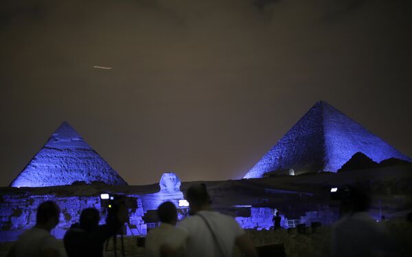 Egyptians watch the historical site of the Giza Pyramids as they are illuminated with blue light, as part of the celebration of the 70th anniversary of the United Nations, in Giza, just outside Cairo, Egypt, Saturday, Oct. 24, 2015 - Sputnik International