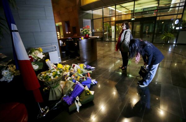 A woman bows after laying flowers to mourn the victims of the attacks on November 13 in Paris, at the French Embassy in Beijing, China, November 15, 2015 - Sputnik International