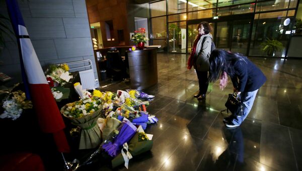A woman bows after laying flowers to mourn the victims of the attacks on November 13 in Paris, at the French Embassy in Beijing, China, November 15, 2015 - Sputnik International