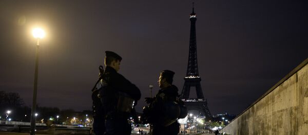 Police officers stand guard near the Eiffel Tower which has its lights turned off on November 14, 2015 following the deadly attacks in Paris. - Sputnik International