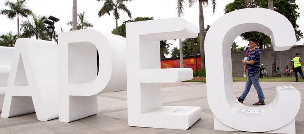 A resident carries his child past an Asia-Pacific Economic Cooperation (APEC) sign in Manila's Rizal park, where the APEC summit will be held next week, in Manila November 15, 2015 - Sputnik International