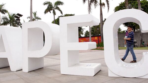 A resident carries his child past an Asia-Pacific Economic Cooperation (APEC) sign in Manila's Rizal park, where the APEC summit will be held next week, in Manila November 15, 2015 - Sputnik International