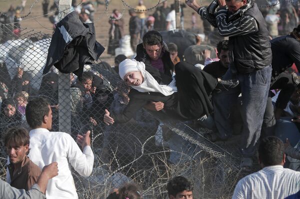 FILE - In this Sunday, June 14, 2015 file photo, Syrian refugees are helped into Turkey after breaking the border fence and crossing from Syria in Akcakale, Sanliurfa province, southeastern Turkey FILE - In this Sunday, June 14, 2015 file photo, Syrian refugees are helped into Turkey after breaking the border fence and crossing from Syria in Akcakale, Sanliurfa province, southeastern Turkey - Sputnik International