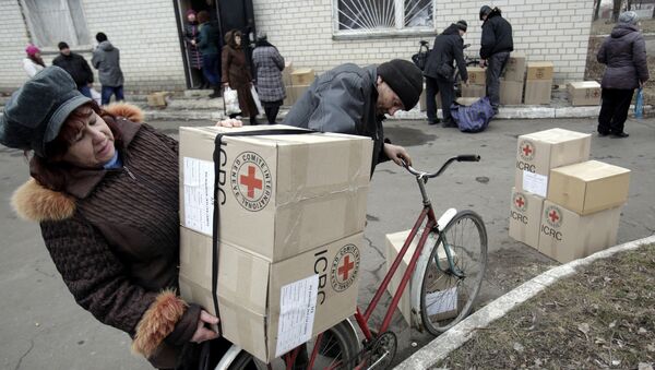 File photo of the residents of the eastern Ukrainian city of Avdiivka, in the Donetsk region controlled by Ukrainian forces, carry boxes containing Red Cross humanitarian aid in Avdiivka on March 2, 2015 - Sputnik International