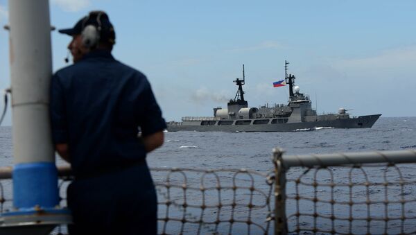 US Navy personnel looks at Philippine Navy vessel BRP Ramon Alcaraz during the bilateral maritime exercise between the Philippine Navy and US Navy dubbed Cooperation Afloat Readiness and Training (CARAT 2014) aboard the USS John S. McCain in the South China Sea near waters claimed by Beijing on June 28, 2014 - Sputnik International