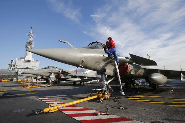 Flight deck crew work on Rafale fighter jets aboard the French nuclear-powered aircraft carrier Charles de Gaulle before its departure from the naval base of Toulon, France, November 18, 2015 - Sputnik International