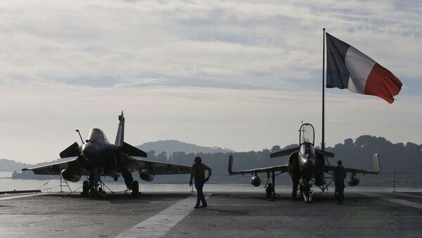 Flight deck crew work around a Rafale (L) and a Super Etendard fighter jets as a French flag flies aboard the French nuclear-powered aircraft carrier Charles de Gaulle before its departure from the naval base of Toulon, France, November 18, 2015 - Sputnik International