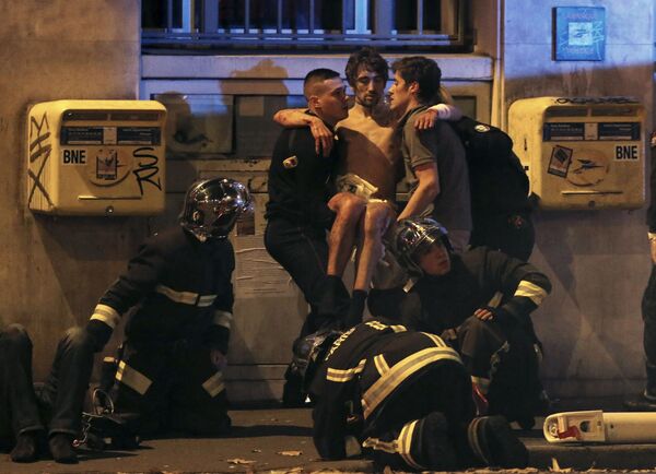 French fire brigade members aid an injured individual near the Bataclan concert hall following fatal shootings in Paris, France, November 13, 2015. - Sputnik International