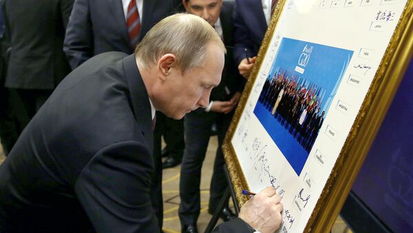 Russian President Vladimir Putin signs a print of the G20-Turkey family photo at the Group of 20 (G20) summit, in the Mediterranean resort city of Antalya, on November 15, 2015 - Sputnik International