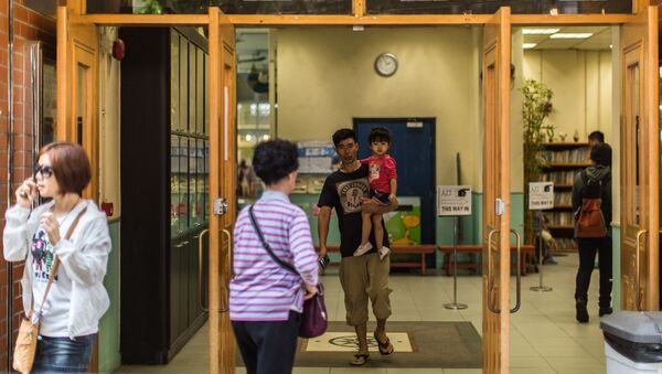 Voters enter and exit a polling station in the Wanchai district of Hong Kong on November 22, 2015 - Sputnik International