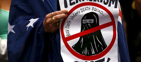 A supporter of the anti-Islam group Reclaim Australia with an Australian national flag drapped around him, holds a placard during a rally in central Sydney, Australia, November 22, 2015 A supporter of the anti-Islam group Reclaim Australia with an Australian national flag drapped around him, holds a placard during a rally in central Sydney, Australia, November 22, 2015 - Sputnik International