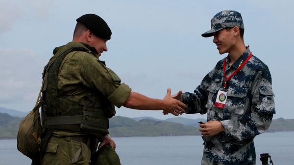 Russian and Chinese servicemen shake hands during the Russian-Chinese drill Naval Interaction-2015 at the Klerk testing grounds in Russia's Primorye Territory. - Sputnik International