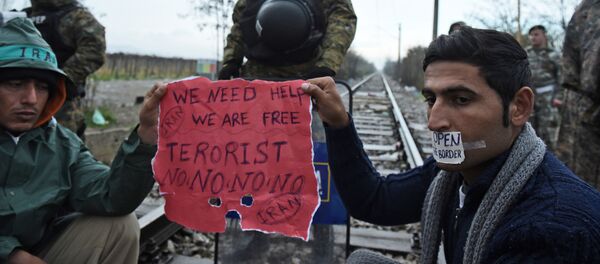 Migrants demanding to be allowed to pass the Greek-Macedonian border sit on the railway tracks in front of Macedonian policemen near the northern Greek village of Idomeni, on Wednesday, Nov. 25, 2015 - Sputnik International