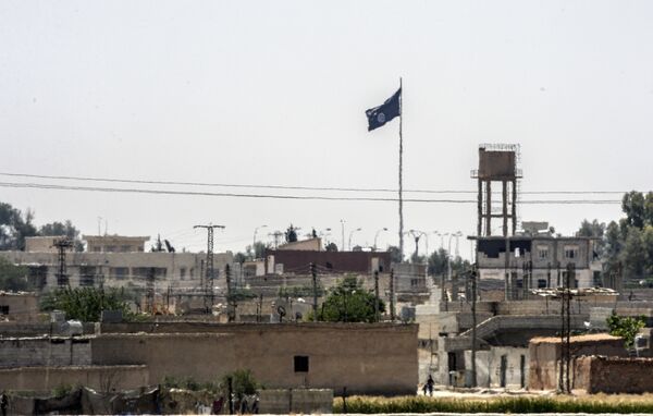 In a picture taken from Alcakale, Turkey, a flag of the Islamic State flutters amongst buildings in the center of the Syrian city Tal Abyad on June 13, 2015 In a picture taken from Alcakale, Turkey, a flag of the Islamic State flutters amongst buildings in the center of the Syrian city Tal Abyad on June 13, 2015 - Sputnik International