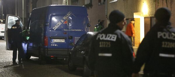 Police officers stand guard as colleagues search a suspicious vehicle during a raid on a building in Britz, south Berlin, Germany - Sputnik International