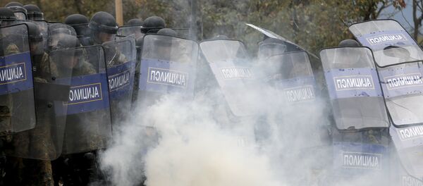 Macedonian police officers try to take cover from tear gas thrown back by a stranded migrant, as minor clashes broke out during a protest against the building of a metal fence at the Greek-Macedonian borders near the village of Idomeni, Greece November 28, 2015 Macedonian police officers try to take cover from tear gas thrown back by a stranded migrant, as minor clashes broke out during a protest against the building of a metal fence at the Greek-Macedonian borders near the village of Idomeni, Greece November 28, 2015 - Sputnik International