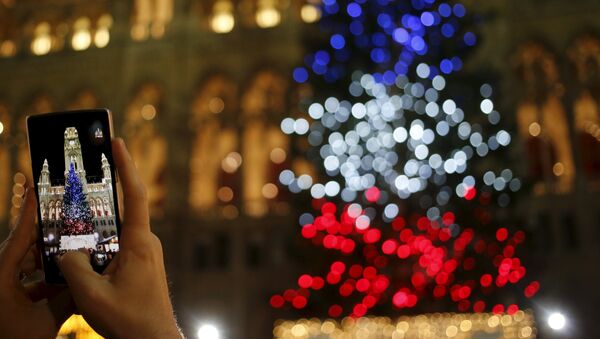 A tourist takes a picture of a Christmas tree lit in the blue, white and red colours of France's national flag in tribute to victims of last Friday's attacks in Paris, in front of the city hall in Vienna, Austria - Sputnik International