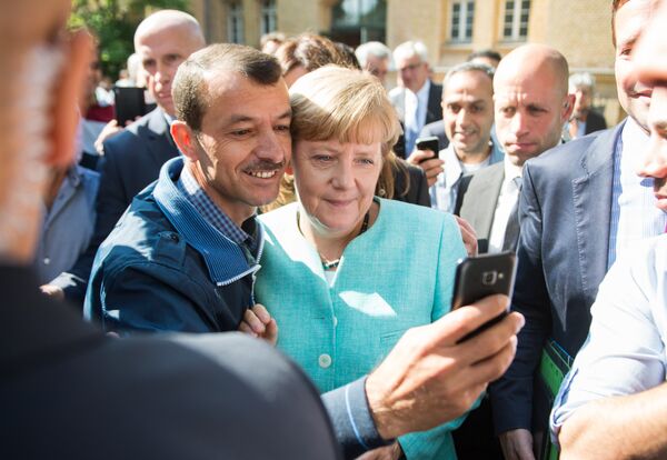 Asylum seeker (C, L) takes a selfie picture with German Chancellor Angela Merkel (C, R) following Merkel's visit at a branch of the Federal Office for Migration and Refugees and a camp for asylum-seekers in Berlin on September 10, 2015. Asylum seeker (C, L) takes a selfie picture with German Chancellor Angela Merkel (C, R) following Merkel's visit at a branch of the Federal Office for Migration and Refugees and a camp for asylum-seekers in Berlin on September 10, 2015. - Sputnik International